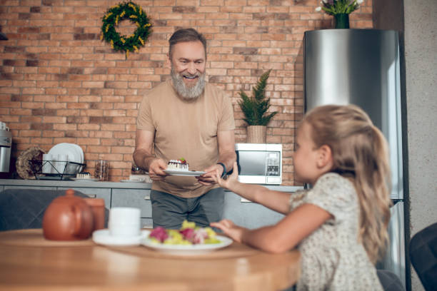 istock Dad smiling and serving table for his cute daughter 1345648861
