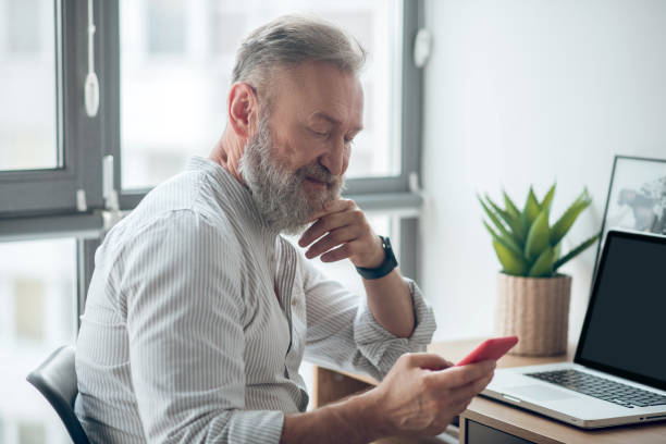 istock A man in white tshirt with a smartphone in hands working at home 1345648903