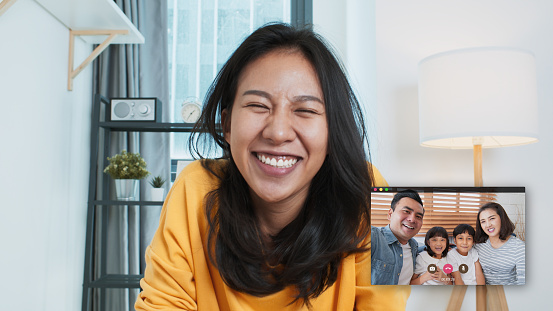 Young Asian family on video call, online remote meeting at home, look at camera. Internet communication information technology, people connection lifestyle, or coronavirus social distancing concept
