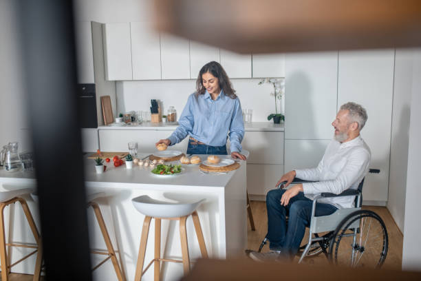 istock Young dark-haired woman preparing breakfast for her disabled husband 1345652621