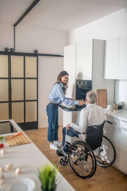istock Young dark-haired woman preparing breakfast for her disabled husband 1345652622