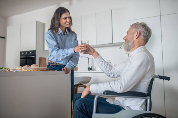 istock Young dark-haired woman preparing breakfast for her disabled husband 1345652629