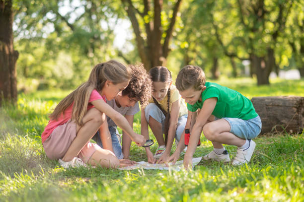 istock Children with map and magnifying glass on lawn 1345656361