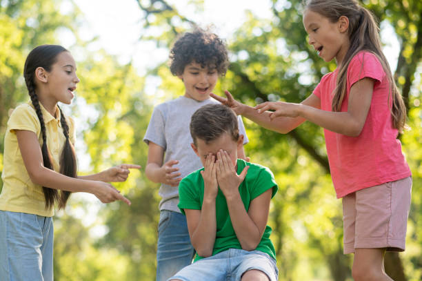 istock Children offending boy covering face with hands. 1345656370