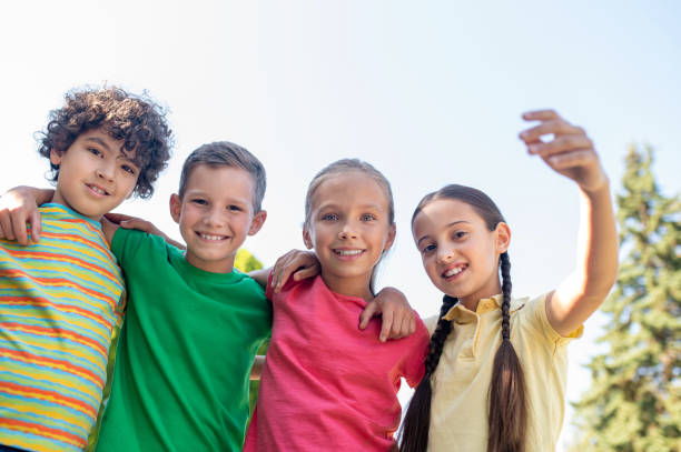 istock Embracing smiling school age friends outdoors 1345656397