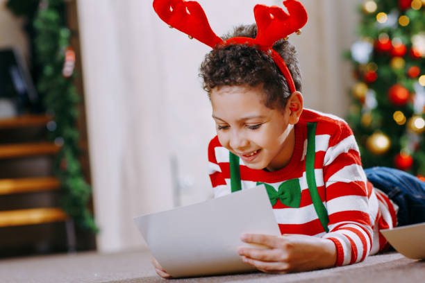 istock A black boy write letter for Santa near a festively decorated Christmas tree 1345657648