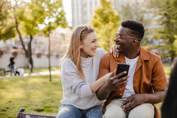 istock Interracial couple in park and using mobile phone 1345658696