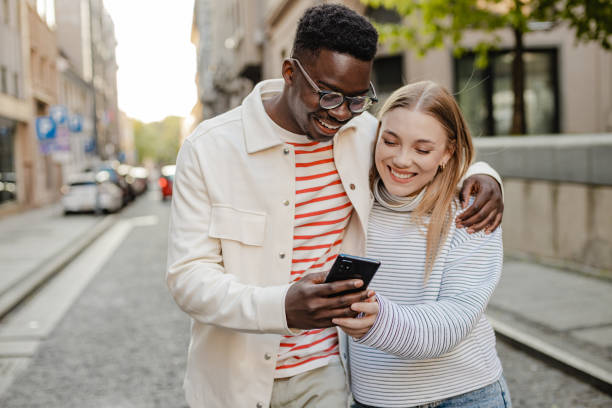 istock Young couple enjoys a walk around the city and using mobile phone 1345658821