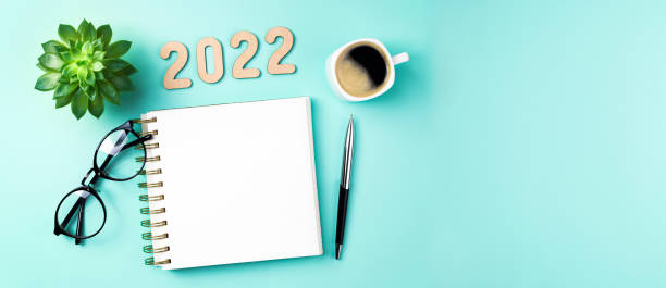 istock New year 2022 goals on desk. 2022 resolutions with open notebook, coffee cup, eyeglasses, plant succulent on green background. Goals, resolutions, plan, strategy, idea concept. New Year 2022 1345666221