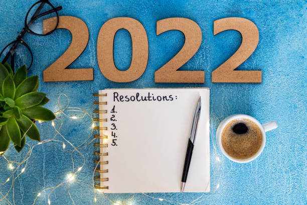 istock New year resolutions 2022 on desk. 2022 goals with notebook, coffee cup and eyeglasses on blue background. Goal, plan, strategy, action, idea concept 1345666240