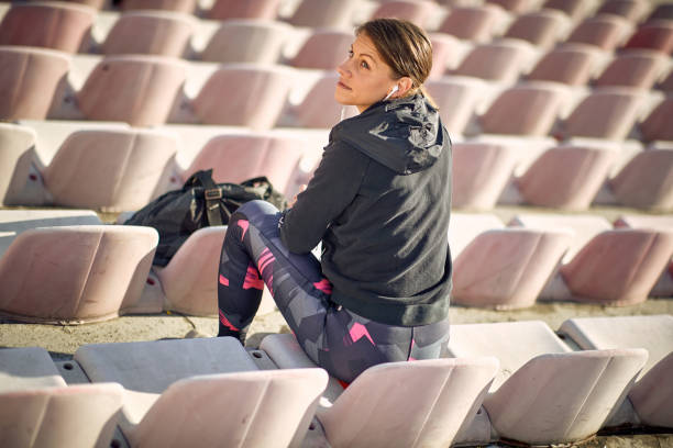 Fit female sitting alone on the bleachers at the daylight