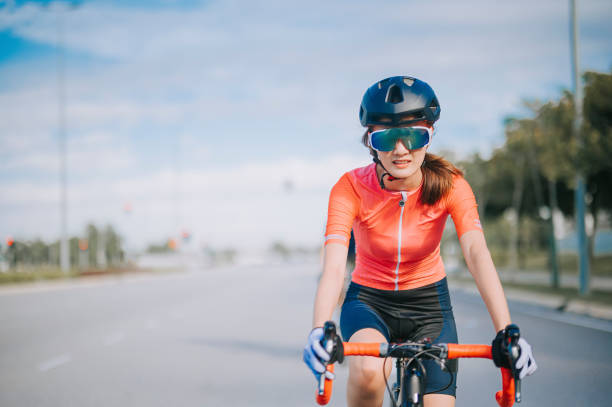 asiatische chinesische junge radfahrerin, die am wochenendmorgen in der stadtstraße rennrad fährt - cyclist cycling road women stock-fotos und bilder