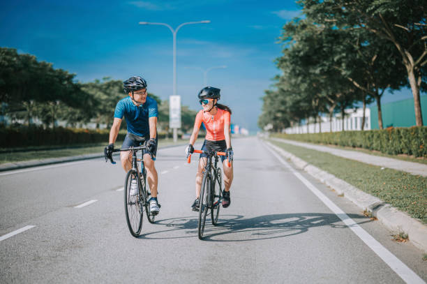 asian chinese couple cyclist enjoy road biking cycling during weekend morning together asian chinese couple cyclist enjoy road biking cycling during weekend morning together cycling vest photos stock pictures, royalty-free photos & images