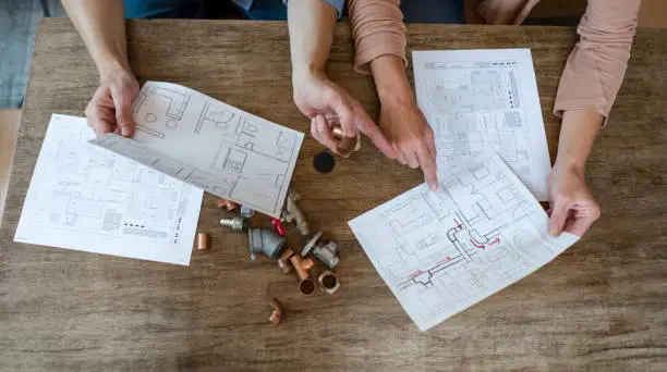 Photo of Couple trying to fix some pipes in the kitchen at home