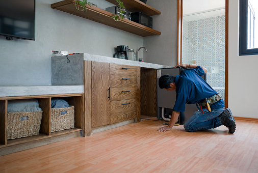Latin American plumber installing a dishwasher at a house - home improvement concepts