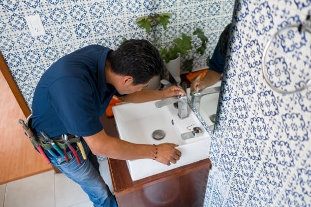 Plumber installing a faucet in a bathroom's sink stock photo