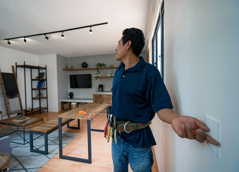 Latin American electrician installing a dimmer to control the lights at a house - home improvement concepts