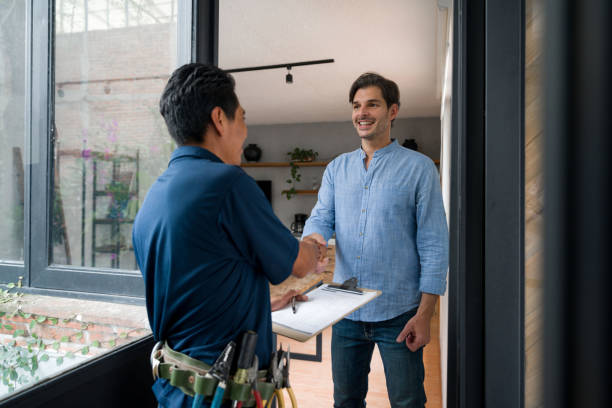 elettricista che saluta un cliente con una stretta di mano alla porta di casa sua - repairman foto e immagini stock