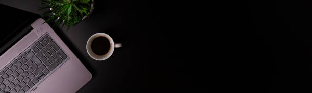istock Copy space office black table with laptop, notebook, pencil and coffee cup with plat. 1345671804