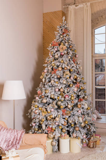 istock Modern living room space, comfortable sofa and christmas tree and presents under it in large suite. Contemporary designer mansion.luxurious expensive light interior living room. 1345671882