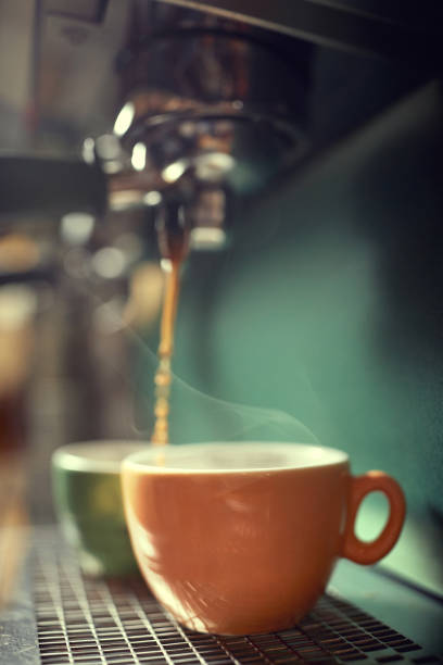 istock Hot coffee preparation. Cup of coffee on coffee maker machine. 1345673095