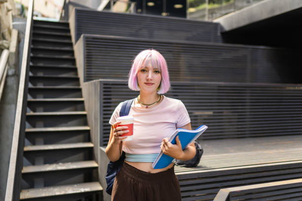 Image of young woman with colorful hair on university campus and holding sustainable coffee cup Image of young woman with colorful hair on university campus and holding sustainable coffee cup pink hair stock pictures, royalty-free photos & images