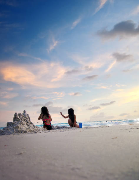 istock Two little girl playing and making sand castle on tropical beach 1345676922