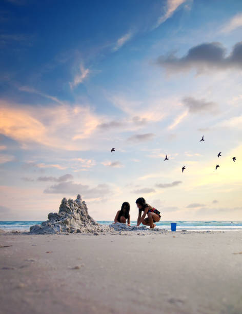 istock Two little girl playing and making sand castle on tropical beach 1345676999