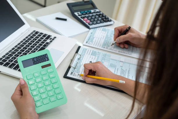 istock Female hands with calculator above 1040 tax form 1345681239