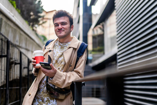 istock Young man holding coffee in cardboard cup and using his smart phone 1345684129