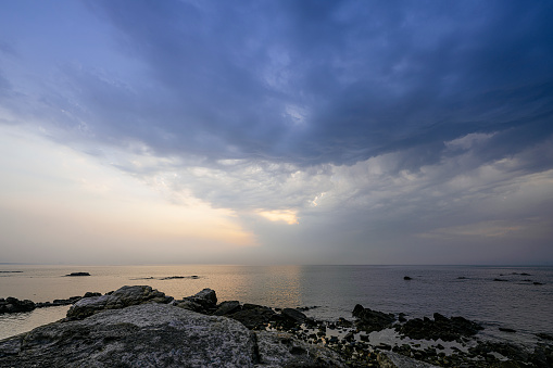 Rocks and changeable clouds on the beach in the early morning of Shandong Province
