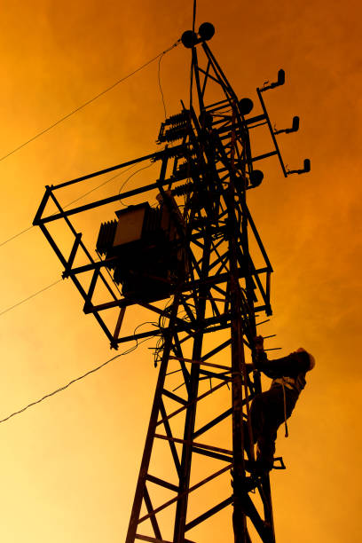 istock Electrician worker climbing electric power pole 1345687101