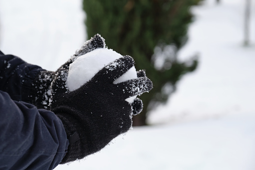Hands with wool globes making a snowball in a park during Filomena snowstorm in Madrid, Spain. Winter activities.