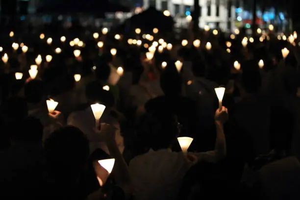 Photo of finding the light in dark. a haza candlelight vigil find each other in darkness, blur background in hong kong victoria park