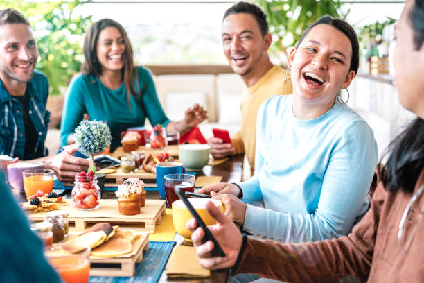 leute unterhalten sich in der kaffeebar im restaurant - freunde, die sich zur brunch-zeit in der cafeteria auf dem dach zusammen vergnügen - life-style-konzept mit glücklichen männern und frauen im café - breakfast eating people teens stock-fotos und bilder