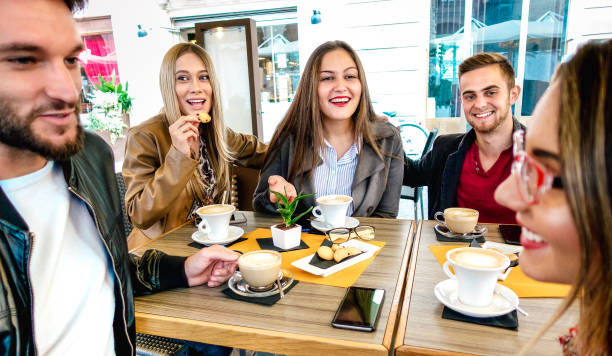 istock People group drinking cappuccino at coffee bar restaurant - Young friends having fun together at outdoor cafeteria - Friendship concept with happy guys and girls at sidewalk cafe  - Warm vivid filter 1345689733