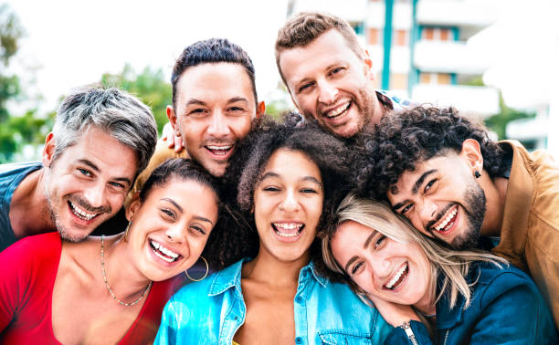 istock Multi generation guys and girls taking selfie outdoors with backlight - Happy milenial friendship concept on young multiethnic people having fun day together 1345690343