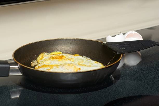istock Eggs frying on stovetop with  shells and spatula 1345690828