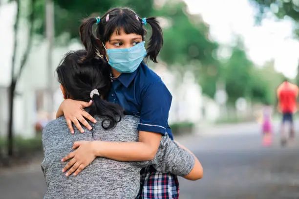 Photo of Daughter hugging her mother before leaving for school after slowdown in Covid-19 pandemic -concept of back to school and new normal lifestyle.