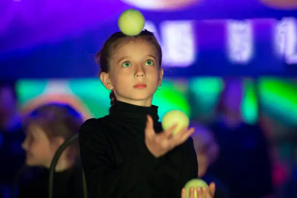 Little girl juggles balls. The circus art of juggling.