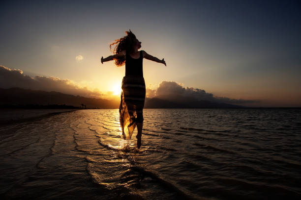 istock Beautiful woman dancing by the sea at sunset 1345694607