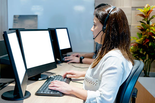 IT service desk operator woman in headset working on computer at call center