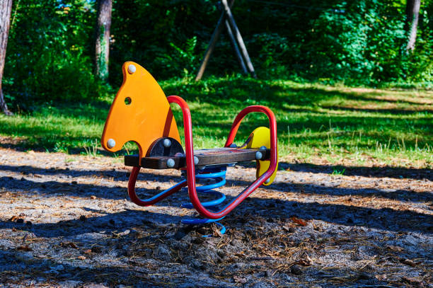 Children's playground with a swing toy in the foreground in a forest.