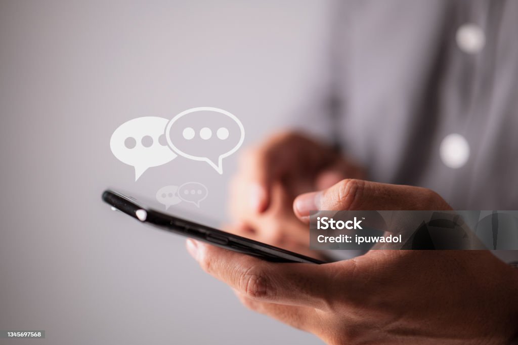 Men hands are typing on their smartphones, and chat box symbols appear. Concept of social media marketing technology. Text Messaging Stock Photo