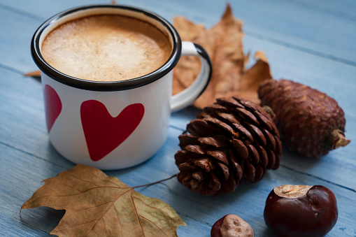 coffee and fall leaves over rustic wood background