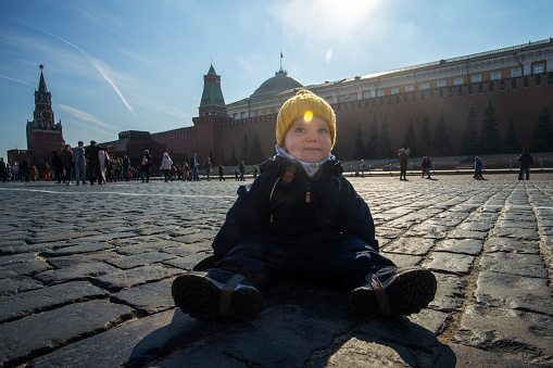 Cute little boy sits on a pavers at Red Square in Moscow