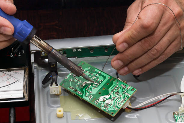 Repairing a faulty DVD player at home Mans hands soldering power supply electronic circuit  of DVD player with electric soldering iron and tin dvd player stock pictures, royalty-free photos & images