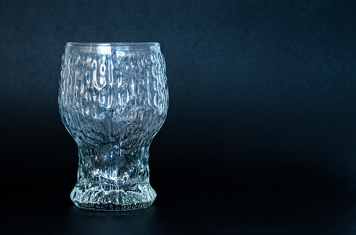 Large glass beaker on a black background. Glassware