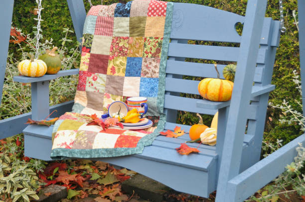 istock Backyard fall harvest decorations on sheltered patio swing bench with cozy blankets for cool autumn days and hot beverage 1345708251