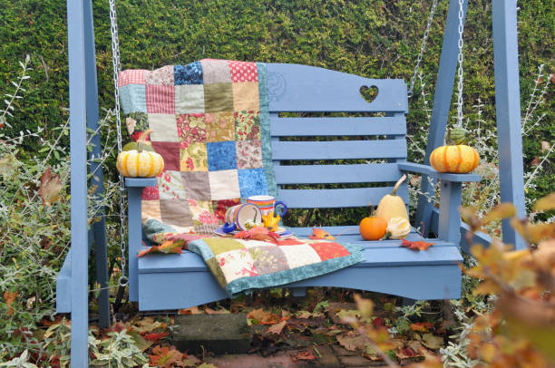 istock Backyard fall harvest decorations on sheltered patio swing bench with cozy blankets for cool autumn days and hot beverage 1345708252